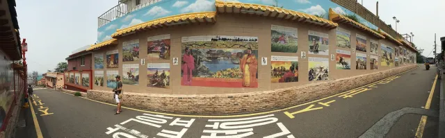 רחוב עם חומה ארוכה מכוסה ציורי קיר וגג רעפים בסגנון סיני